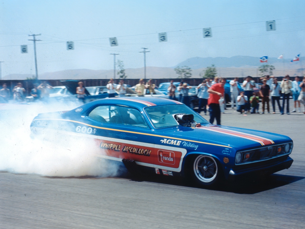 Whipple-McCulloch Duster burnout with spectators in the background.