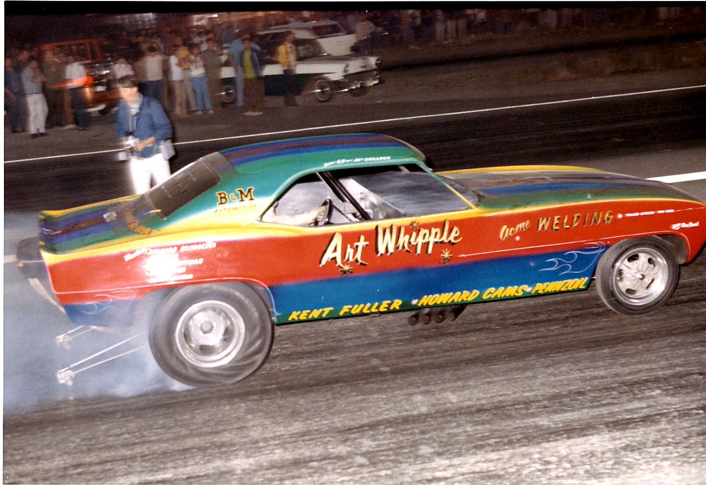 Side profile of a Whipple funny car under the lights during a pass.